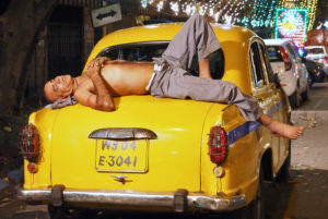 Taxifahrer ruht sich auf seinem gelben Auto aus